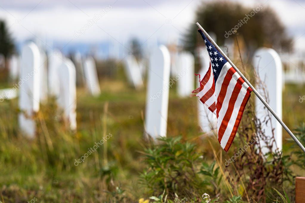 A wooden white grave mark with the United States flag in the Nome Cemetery, Alaska, shallow dof.
