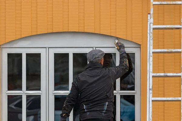 Travailleur inuit peignant une fenêtre avec un pinceau à l'extérieur à Nuuk . — Photo