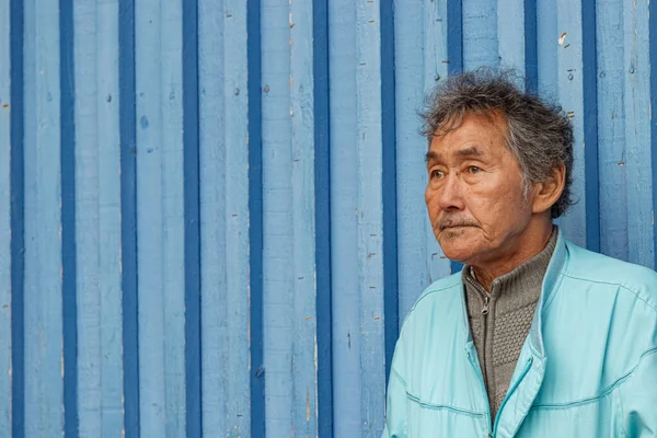 Portrét inuitského místního zralého muže, který se dívá přes pruhovanou zeď v Nuuku. — Stock fotografie