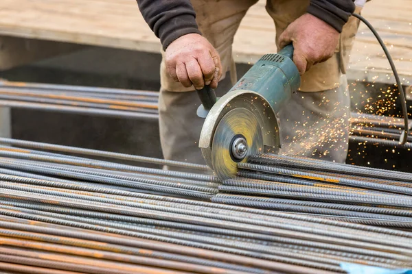 Mannelijke handen snijden stalen staven met een ronde elektrische slijper. — Stockfoto