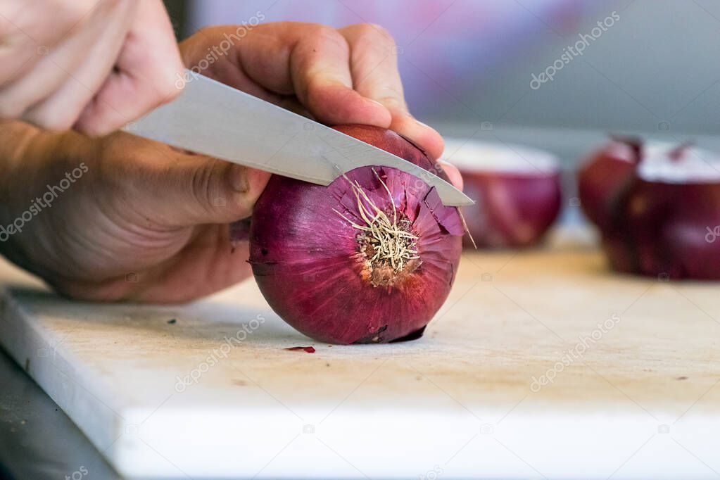 Male hand cutting - chopping red onions, sun light.