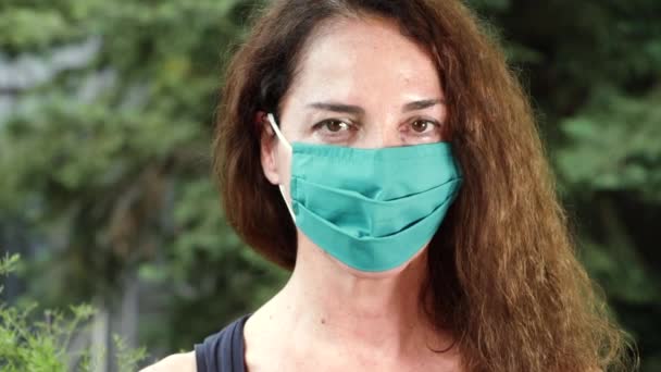 Retrato de uma mulher usando uma máscara protetora no verão olhando câmera, ao ar livre — Vídeo de Stock