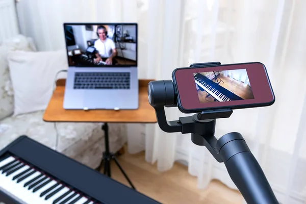Смартфон, розміщений на гільзі, використовується як друга камера для онлайн уроків фортепіано . Стокове Зображення