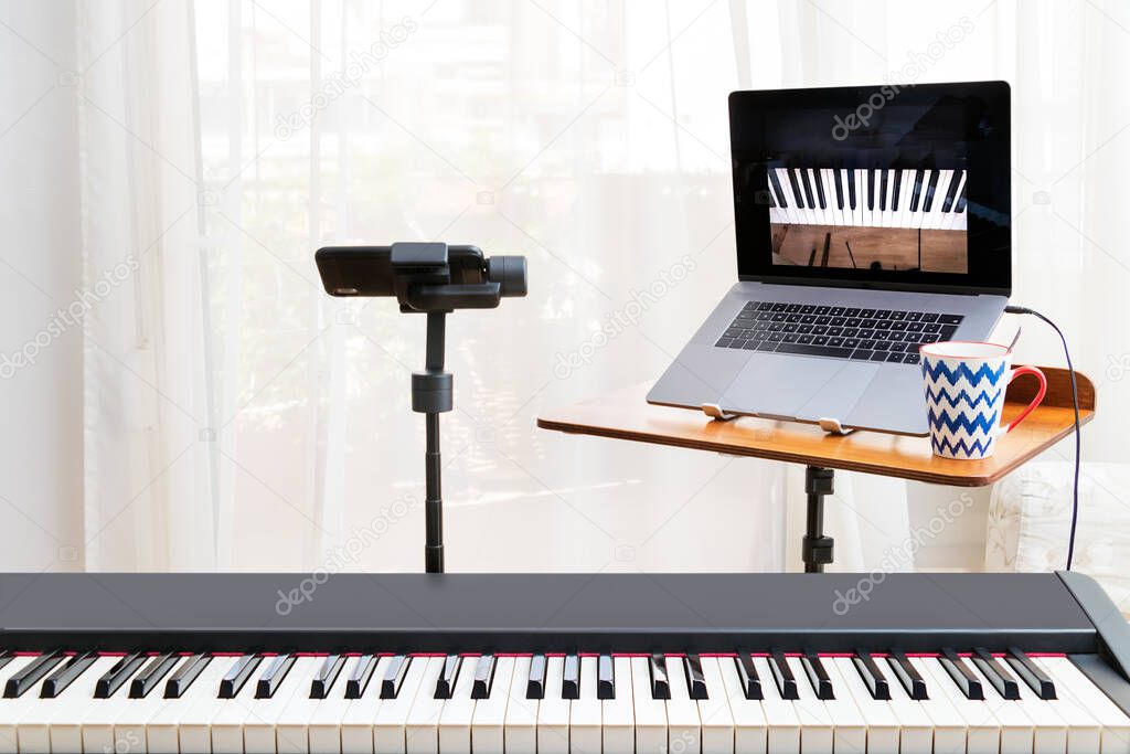 Online piano lessosn setup with a laptop, a piano keyboard and a smartphone on a gimbal as camera.