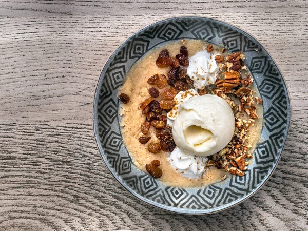 Top view of a greek halva - semolina with raisins, chopped nuts and ice cream on a plate. — Stock Photo, Image