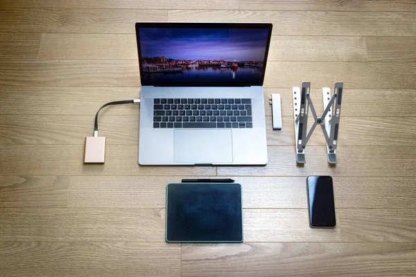 Bovenaanzicht van een laptop met een grafische tablet, een mobiele telefoon, een opvouwbare standaard, een SSD harde schijf en een hub type C adapter — Stockfoto