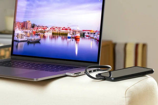 Смартфон заряджається підключеним до адаптера вузла на ноутбуці Стокова Картинка