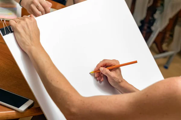 Female hand holding a wooden pencil ready to draw a sketch paint on a white paper — Stock Photo, Image
