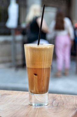 Soğuk bir Yunan kahvesi, açık havada tahta bir masaya yerleştirilmiş freddo kapuçino..