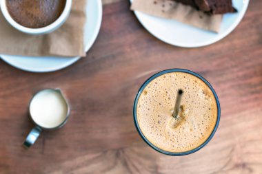 Soğuk bir Yunan kahvesinin üst görüntüsü, Freddo. Dışarıdaki ahşap bir masaya konmuş frape espresso.