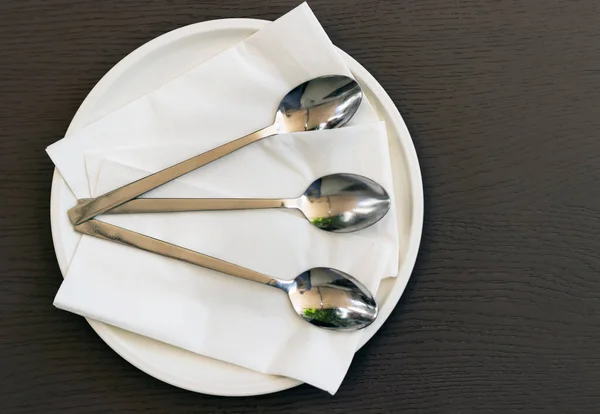 Vista superiore di tre cucchiai su un piatto con tovaglioli su un tavolo — Foto Stock