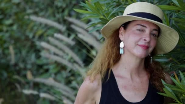 Porträtt av en kvinna 40-45 år ser kameran bär casual kläder och en halm hatt, allvarliga. — Stockvideo