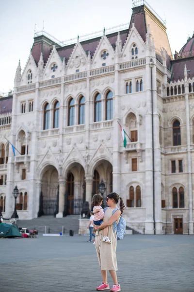 mother and little daughter walk in the square near the Hungarian Parliament