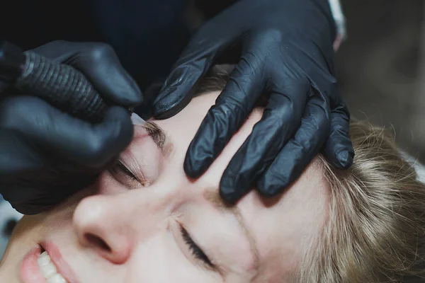 master in black gloves does permanent eyebrow makeup