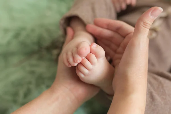 Pés de bebé nas mãos da mãe. Pequenos pés de bebê recém-nascido em mulheres em forma de mãos closeup. A mãe e o filho. Conceito de família feliz. Bela imagem conceitual da maternidade — Fotografia de Stock