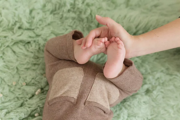 Pés de bebê na mão da mãe no tapete verde. vista traseira — Fotografia de Stock