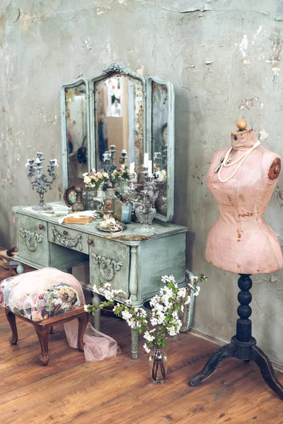 vintage room in a photo studio with a vintage wooden dressing table with a big mirror, vases with flowers, a pink mannequin