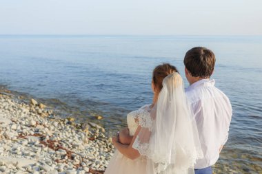 Gelin ve damat sarılıyor ve denize bakıyorlar.