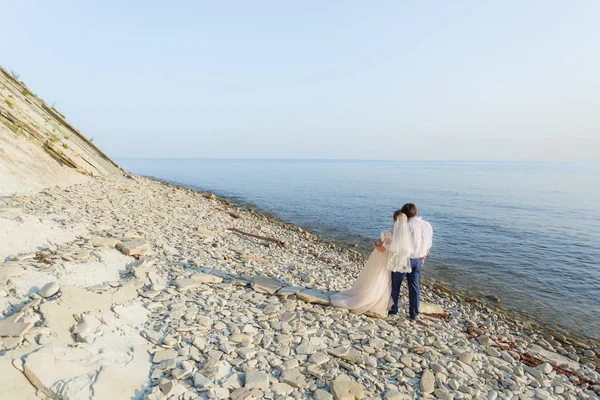 Bride and groom are hugging and looking at the sea — Stock Photo, Image