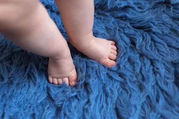 Pequenos pés de bebê fazendo o primeiro passo no tapete azul — Fotografia de Stock