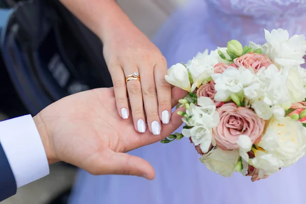 Mãos de noiva e noivo com anéis no buquê de casamento. Conceito de casamento — Fotografia de Stock