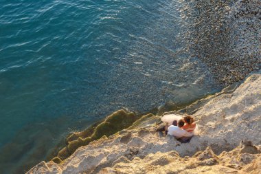 gün batımına bakan deniz plajında oturan genç çift