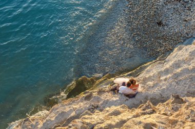 gün batımına bakan deniz plajında oturan genç çift