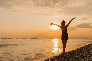 Mutlu Kaygısız Kadın Sahilde Güzel Günbatımının tadını çıkarıyor