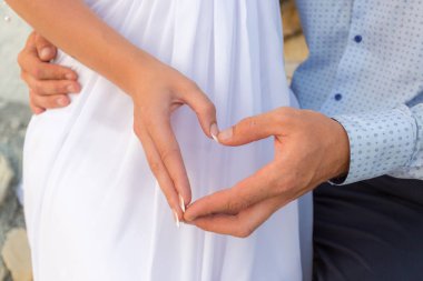 Elleriyle kalp şekillendiren çiftin yakın çekimi.