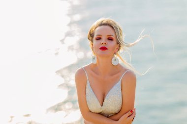 Sahilde güzel, seksi bir kadın. Sıska vücutlu, şık bir kadın, deniz kenarında yürüyor.