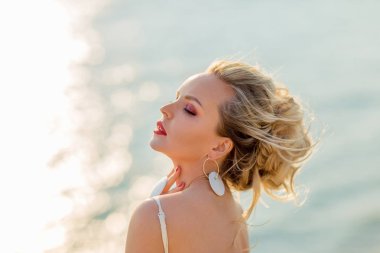 Sahilde parlak makyajlı güzel ve seksi bir kadının yakın plan portresi.