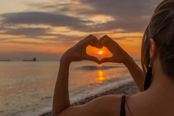 Siluet el kalbe saplanmış, ortası ve sahili güneş doğuyor.