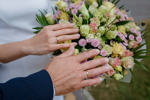 Mãos de noiva e noivo com anéis no buquê de casamento. Conceito de casamento — Fotografia de Stock