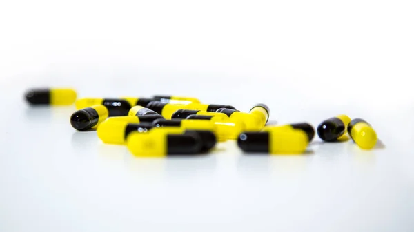 Закрытие черных и желтых таблеток и таблеток медицины на белом фоне . — стоковое фото