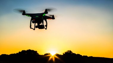 Gün batımı ile bir alan üzerinde dijital fotoğraf makinesi ile uçan drone görünümü