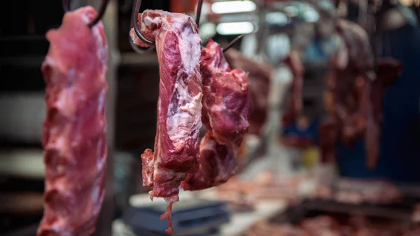 Closeup of fresh raw pig meat hanging in an asian stall. Traditional market.