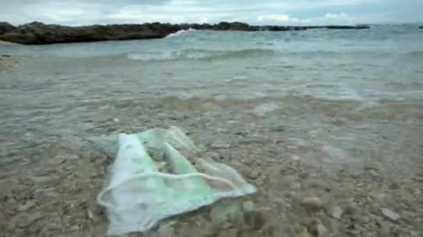 コロナウイルスプラスチック廃棄物環境汚染 使い捨てマスクは海でゴミを発生させます 使い捨て医療用マスクを海に浮かべる廃棄物 — ストック動画