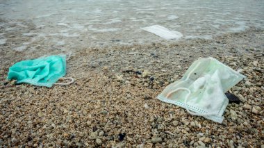 COVID-19 sırasında israf. Okyanus koronavirüsüne atılmış tek kullanımlık yüz maskeleri. Çevre ve sahil plastik kirliliği. Sahildeki çöpler okyanusların sağlığını tehdit ediyor..