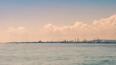 Sanayi manzarası okyanustan enerji santrali sanayi bölgesini gösteriyor. Sahildeki petrol rafinerisi. İnsanlığın ekolojik sorunu. Deniz kirliliği kavramı.