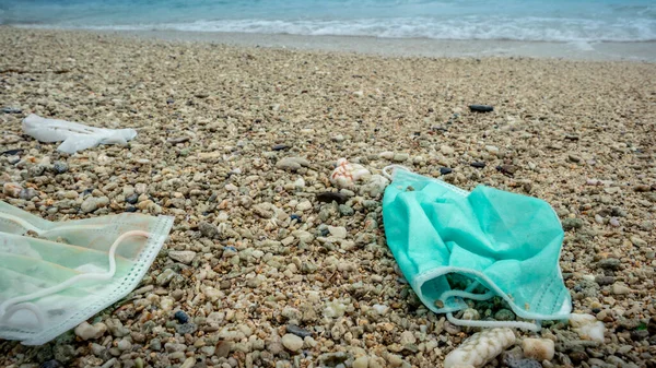 Coronavirus polluting the environment. The waves wash up old used medical mask waste. The personal protective equipment get into the water, they pose a threat to marine life.