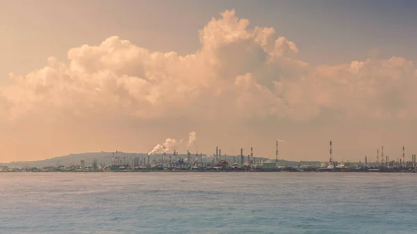 Industrial landscape view from the ocean at power plant form industry zone. Oil refinery on the coast. Ecological problem of humanity. Sea pollution concept.