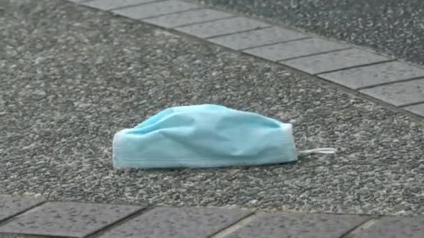 医疗面罩在街上的地板上 不适当地丢弃杂乱无章地散落在人行道上的旧外科口罩 丢失的一次性口罩 以保护考文19 Dan — 图库视频影像