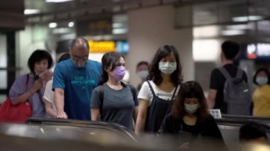 Taipei, Tayvan-07 Haziran 2020: 4K, metro girişindeki yürüyen merdivenlerde bulaşıcı hastalıklara karşı koruyucu maske takan Asyalılar tren istasyonuna gidiyor. Coronavirus koruması - Dan