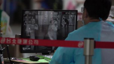 Taipei, Tayvan-04 Haziran 2020: Ağır çekim Tayvan sağlık bakanlığı yetkilisi metro istasyonundaki yolcuların sıcaklıklarını kontrol etmek için termal tarayıcı kullanıyor. Coronavirus-Dan sırasındaki ihtiyati tedbirler