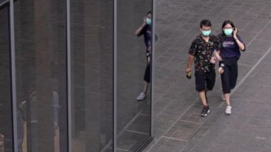 Taipei, Tayvan-31 Mayıs 2020: Küresel Coronavirüs salgını sırasında koruyucu maskeler takan yavaş hareket eden insanlar. Asyalı yayalar modern bir binanın yansıma camlarıyla sokakta yürüyorlar.