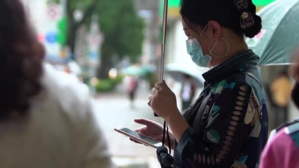 台湾台北6月7日电 2020 在雨天 亚洲女人头戴医用防护面罩 手持智能手机 手持雨伞 动作缓慢 生活方式珊瑚的概念 — 图库视频影像