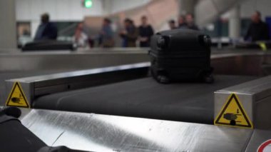 4k, havaalanı uluslararası terminal binasının varış salonundaki bagaj teslim yerinde valiz taşıma bandındaki bavul. Bekleme salonundaki insanlar bavullarını ve çantalarını topluyorlar. Seyahat kavramı - Dan