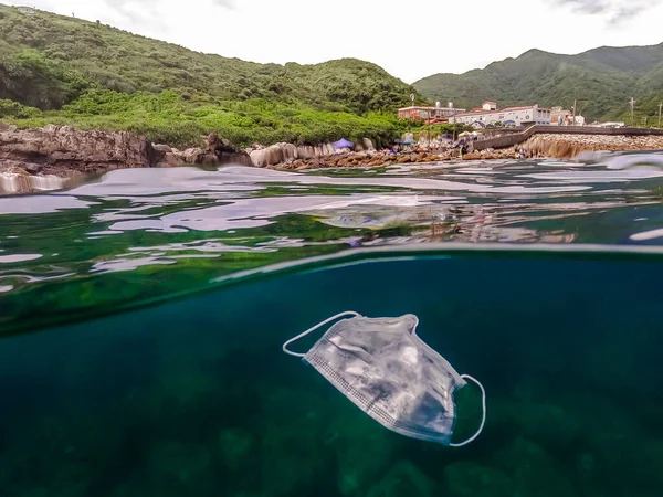 医疗面罩漂浮在水下 在海水上使用外科口罩 — 图库照片