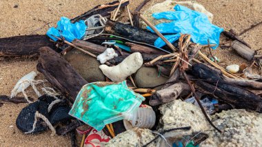 Tıbbi atıklar, maskeler ve plastik eldivenler deniz kıyısındaki çöpler. Coronavirus covid-19 çevre kirliliği hastalığı. Kumsala atılmış mavi cerrahi maske kullanılmış..