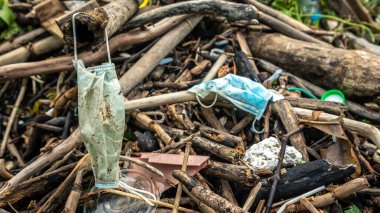 Tıbbi atıklar, maskeler ve plastik eldivenler deniz kıyısındaki çöpler. Coronavirus covid-19 çevre kirliliği hastalığı. Kumsala atılmış mavi cerrahi maske kullanılmış..